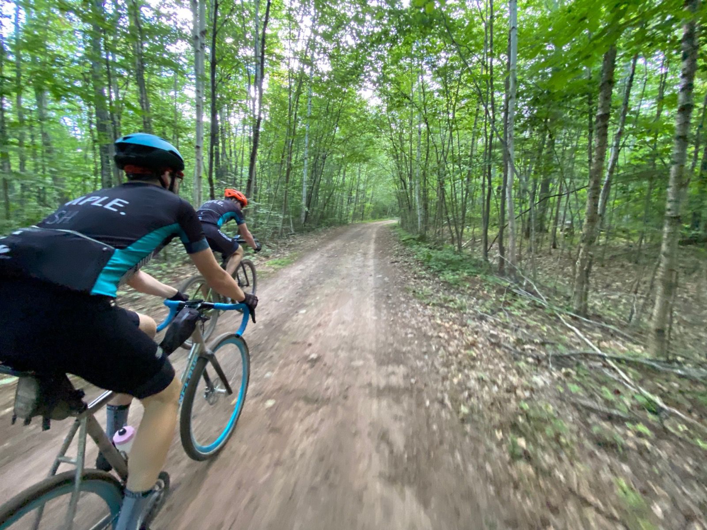 Two gravel cyclists riding on a wooded road during MK Ultra Gravel.
